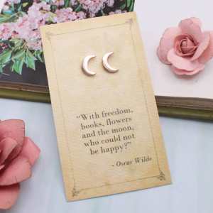 Gold-tone crescent moon stud earrings on an Oscar Wilde quotation card.
